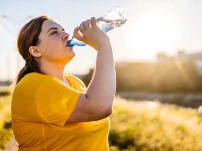 A woman drinking from a water bottle after exercising