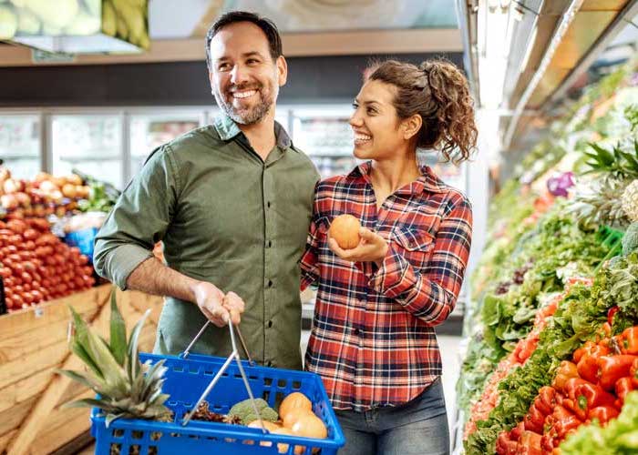 A man and woman food shopping at a grocery store