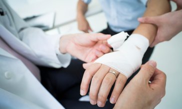 El médico envuelve un vendaje en el brazo del paciente herido.