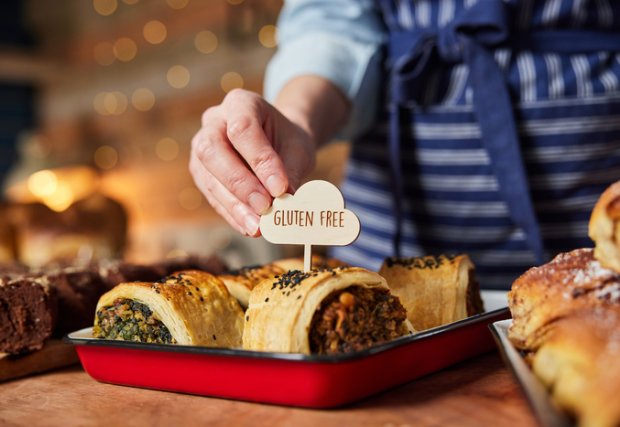 Sales Assistant In Bakery Putting Gluten Free Label Into Freshly Baked Savoury Roll