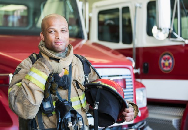 fireman standing in front of a fire engine parked at the station