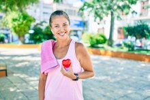 Middle age sportswoman asking for health care holding heart at the park